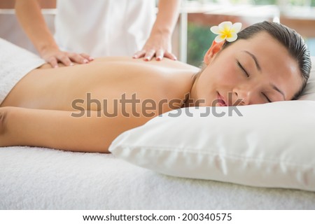 Smiling brunette getting a back massage at the health spa