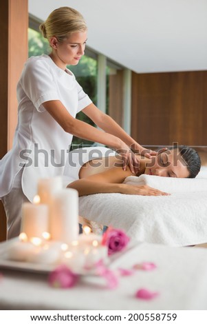 Smiling brunette getting a shoulder massage at the health spa