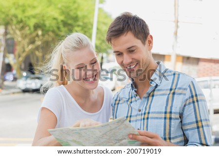 Young tourist couple consulting the map on a sunny day in the city