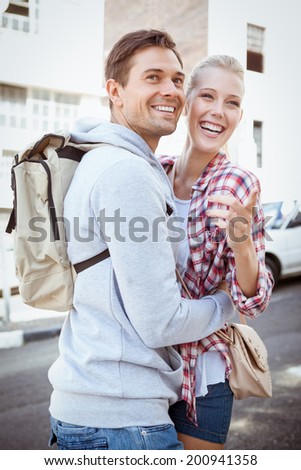 Young tourist couple smiling and pointing at something on a sunny day in the city