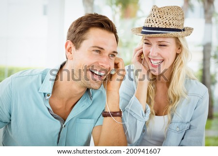 Hip young couple listening to music together on the cafe terrace on sunny day