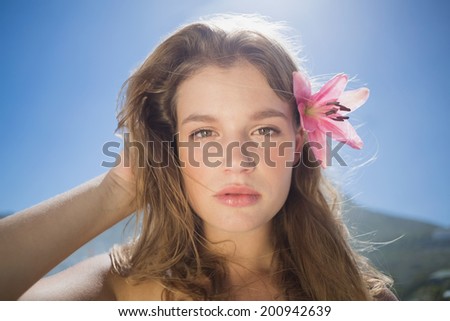 Beautiful blonde with flower hair accessory on the beach on a sunny day