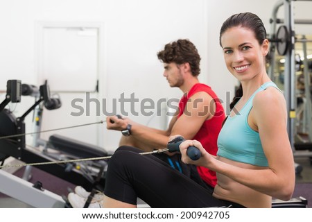 Smiling brunette working out on the rowing machine at the gym