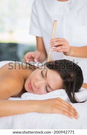 Relaxed brunette getting an ear candling treatment at the spa