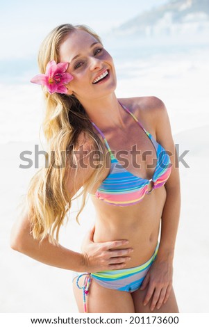 Gorgeous blonde in bikini smiling at camera on the beach on a sunny day