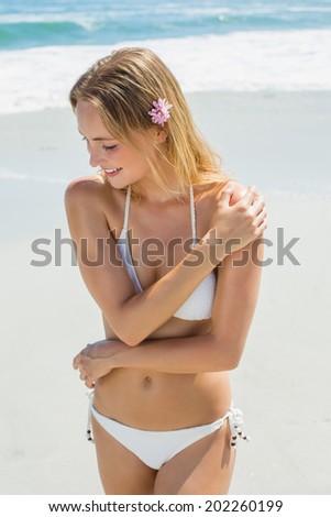 Beautiful blonde in white bikini smiling on the beach on a sunny day
