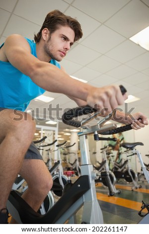 Focused fit man on the spin bike at the gym