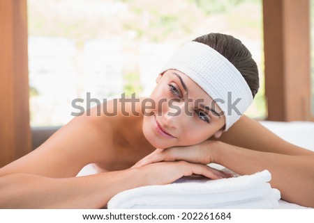 Beautiful smiling brunette lying on massage table in the health spa