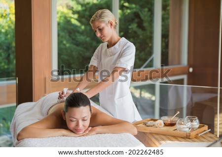 Content brunette enjoying a herbal compress massage at the health spa