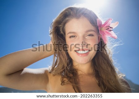 Beautiful smiling blonde with flower hair accessory on the beach on a sunny day