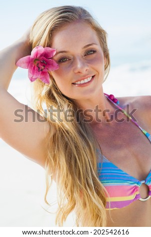 Gorgeous blonde in bikini smiling at camera on the beach on a sunny day
