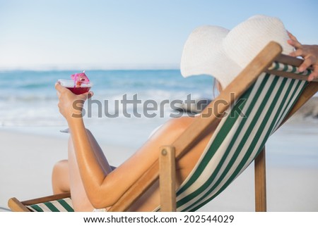 Woman relaxing in deck chair with cocktail on a sunny day