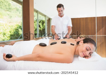 Pretty friends lying on massage tables getting hot stone massages in the health spa