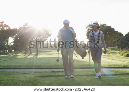 Golfing couple walking and chatting on a sunny day at the golf course
