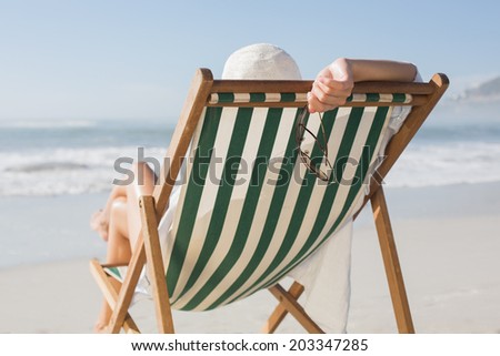 Woman relaxing in deck chair by the sea on a sunny day
