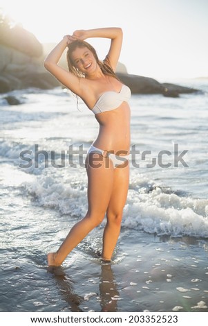 Beautiful smiling blonde in white bikini at the beach with wet hair on a sunny day