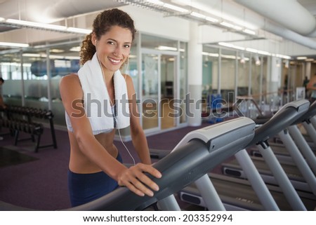 Fit woman wearing towel around shoulders on the treadmill at the gym