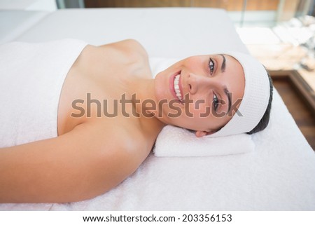 Peaceful smiing brunette lying on massage table in the health spa