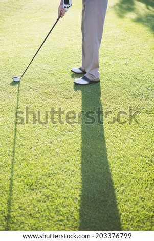 Golfer standing on the putting green on a sunny day at the golf course