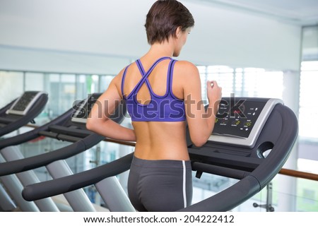 Fit brunette running on the treadmill at the gym