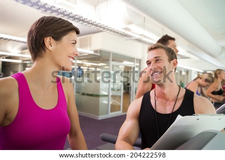 Trainer talking to his client on the treadmill at the gym