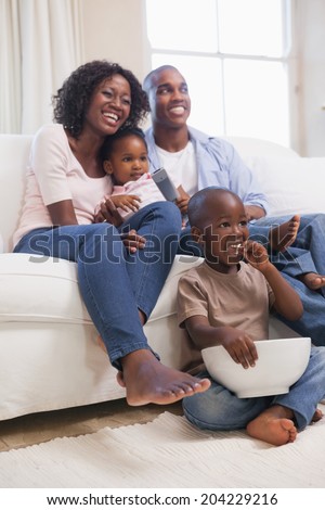 Happy family sitting on couch together watching tv at home in the living room