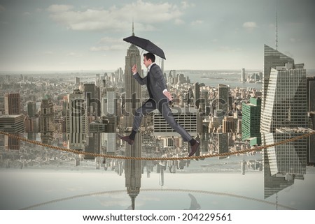 Businessman jumping on tightrope holding an umbrella against room with large window looking on city