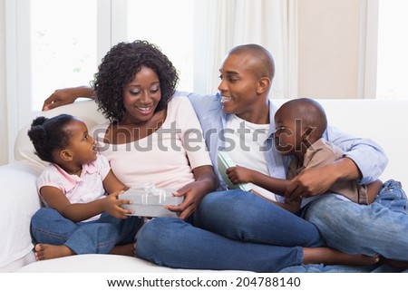 Happy family on the couch giving mother presents at home in the living room