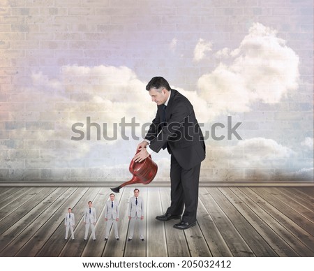 Mature businessman watering tiny businessman against clouds in a room
