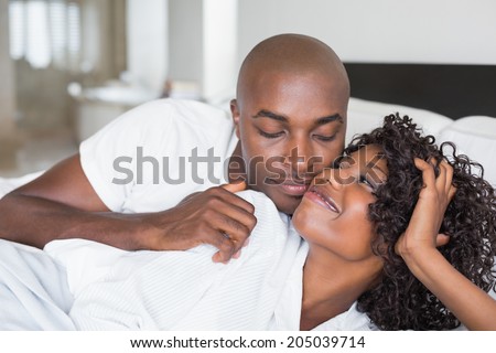 Happy couple lying in bed together at home in the bedroom