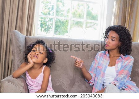 Pretty mother scolding her daughter on the couch at home in the living room