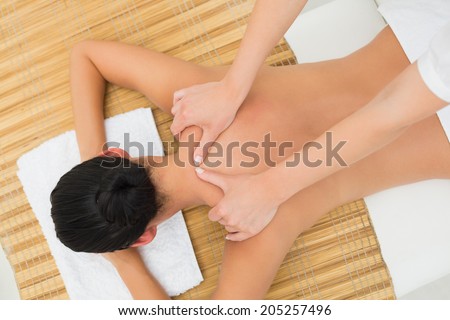 Peaceful brunette enjoying a shoulder massage in the health spa