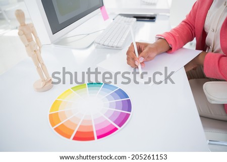 Casual graphic designer working at her desk sketching in her office