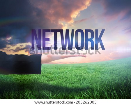 Businesswomans hand presenting the word network against green field under orange sky