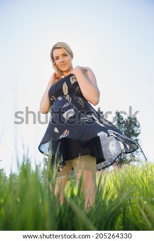 Pretty blonde in sundress smiling at camera on a sunny day in the countryside