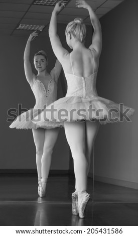 Graceful ballerina standing en pointe in front of mirror in the ballet studio