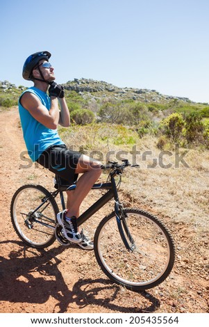Fit cyclist fixing strap on helmet on a sunny day