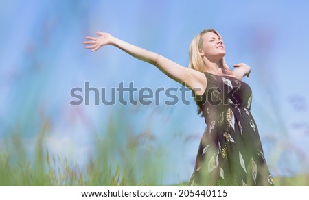 Pretty blonde in sundress standing with arms out on a sunny day in the countryside