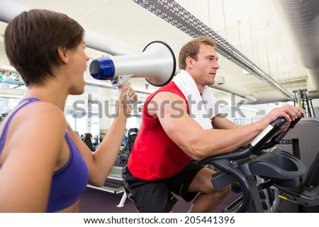 Personal trainer shouting at client through megaphone at the gym