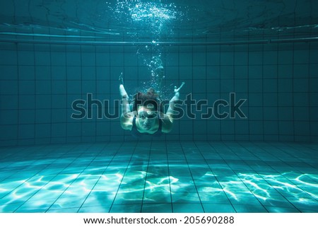 Athletic swimmer smiling at camera underwater in the swimming pool at the leisure centre