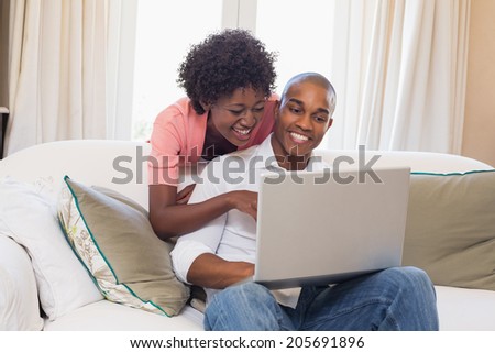 Cute couple relaxing on couch with laptop at home in the living room