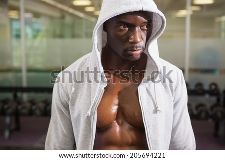 Muscular young man in hood jacket at the gym