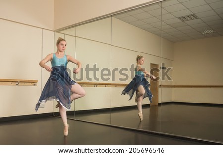Beautiful ballerina dancing in front of mirror in the dance studio