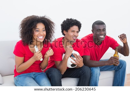 Football fans in red sitting on couch cheering on white background