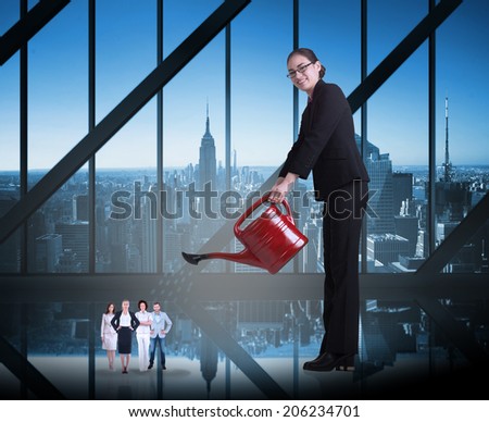 Businesswoman watering tiny business team against room with large window looking on city