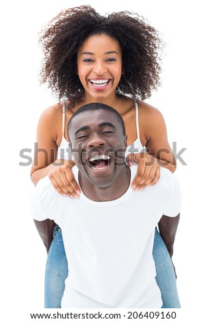 Casual man giving his smiling girlfriend a piggy back on white background