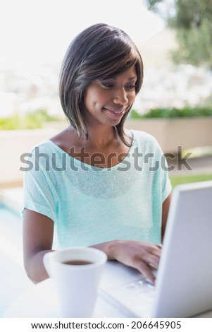 Pretty woman sitting outside using laptop on a sunny day