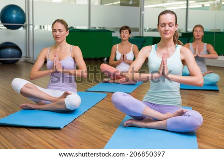 Smiling yoga class in lotus pose in fitness studio at the leisure center
