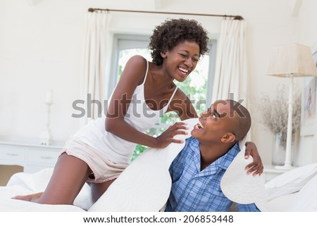 Silly couple having fun on bed together at home in the bedroom