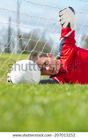 Goalkeeper in red making a save on a clear day